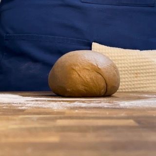 Una palla di pasta è appoggiata su un tavolo di legno.