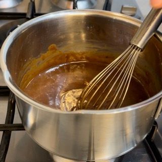 Una persona sta mescolando una salsa in una pentola sul fornello.