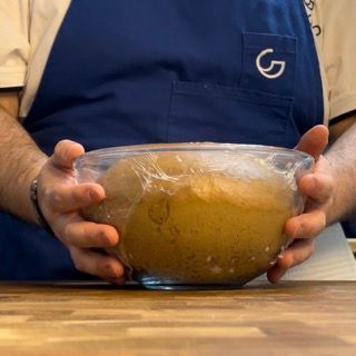 Un uomo con un grembiule blu tiene in mano una ciotola di cibo