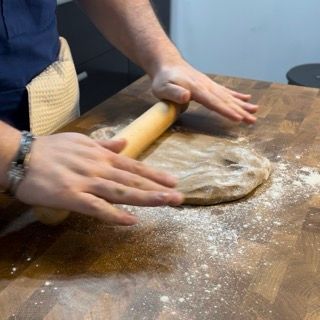 Una persona sta stendendo la pasta con un mattarello