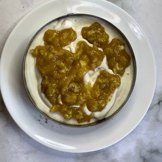 Un piatto bianco sormontato da una ciotola di yogurt e salsa