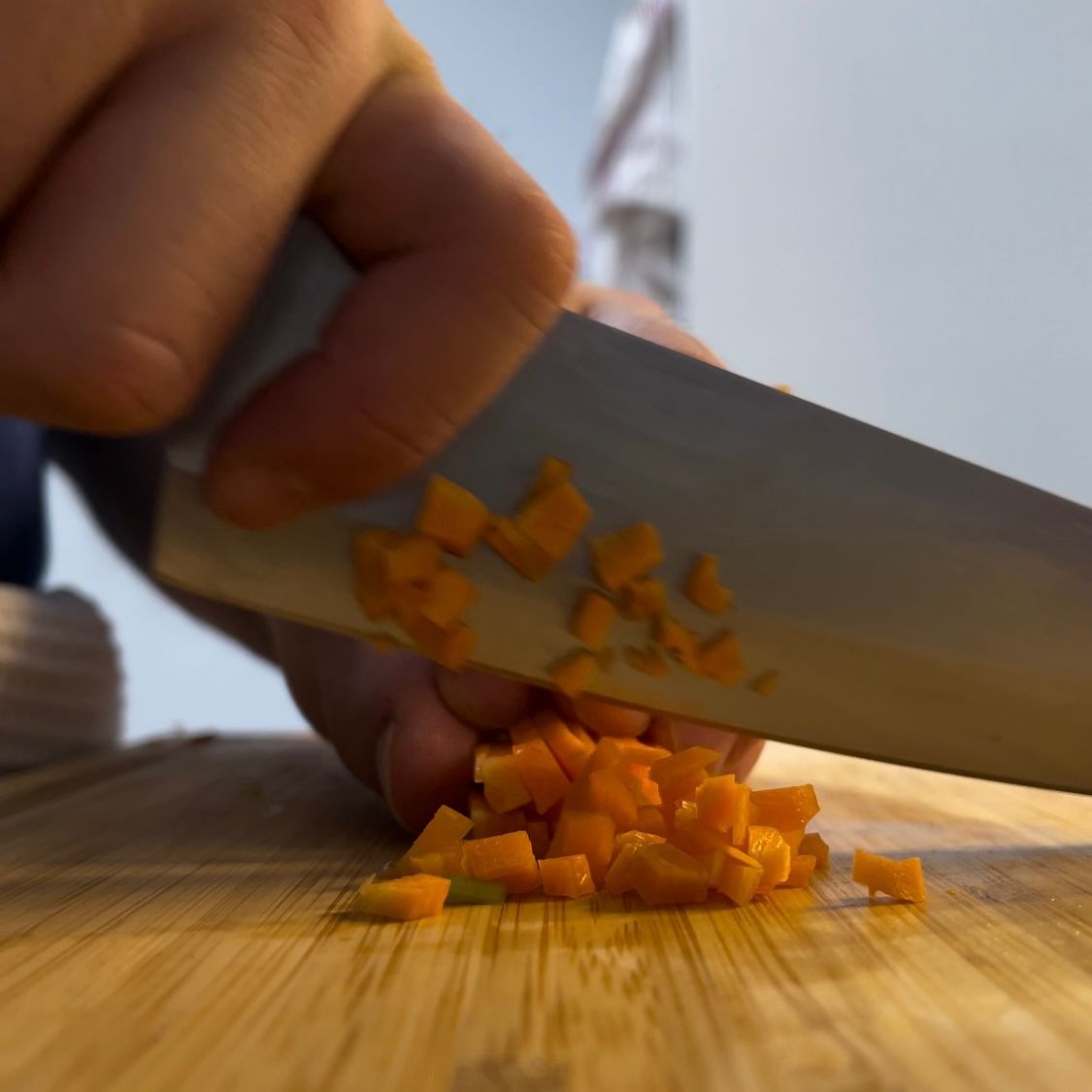 Verdure per il soffritto tritate finemente al coltello su un tagliere.