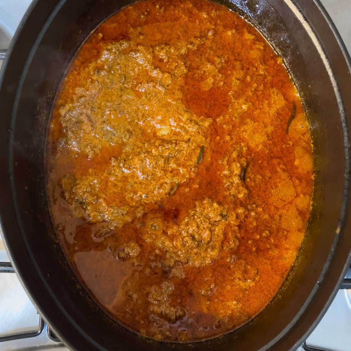 Primo piano del ragù durante le 4 ore di cottura, denso e scuro.