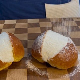 Due panini ricoperti di zucchero a velo sono appoggiati su un tavolo a scacchi