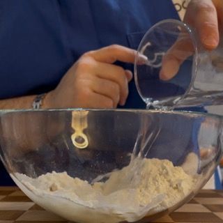 Una persona sta versando acqua in una ciotola di farina