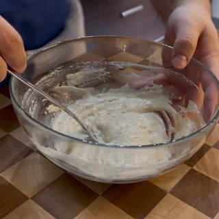 Una persona sta mescolando qualcosa in una ciotola con un cucchiaio