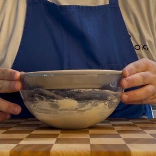 Una persona con un grembiule tiene in mano una ciotola di cibo