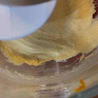 Una persona sta mescolando un impasto in una ciotola di vetro con un mixer.