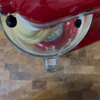 Un mixer rosso è appoggiato su un tagliere di legno