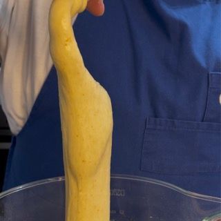 Una persona con un grembiule blu tiene in mano un oggetto giallo