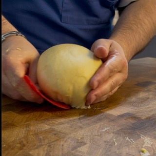 Una persona sta sbucciando una mela con un cucchiaio rosso