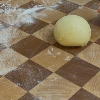 Una palla di pasta è appoggiata su una superficie di legno a scacchi
