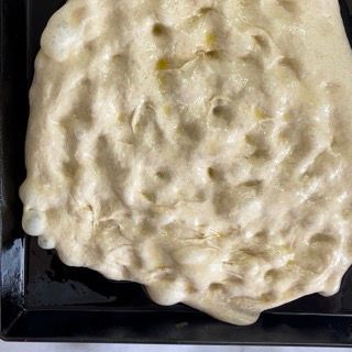 Un impasto per pizza è appoggiato su una padella nera.