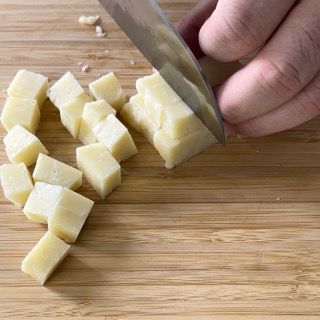 Una persona sta tagliando un pezzo di formaggio su un tagliere