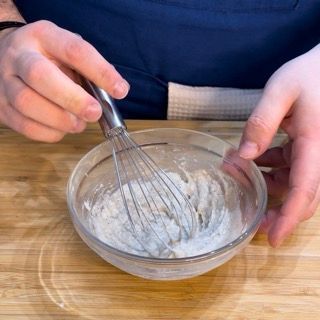 Una persona sta mescolando qualcosa in una ciotola con una frusta