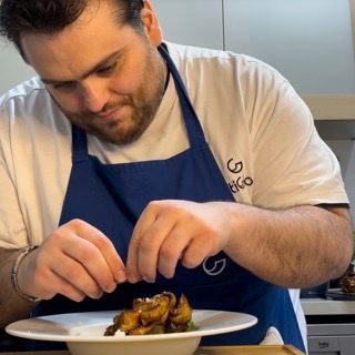 Un uomo che indossa un grembiule blu sta preparando il cibo
