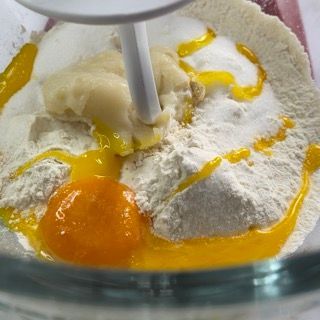 Una ciotola di vetro piena di farina, uova e burro