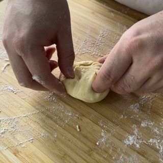 Una persona sta impastando la pasta su un tagliere di legno