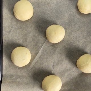 Un mucchio di palline di pasta sono appoggiate su un pezzo di carta oleata