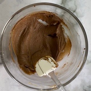 Una ciotola di glassa al cioccolato con una spatola dentro