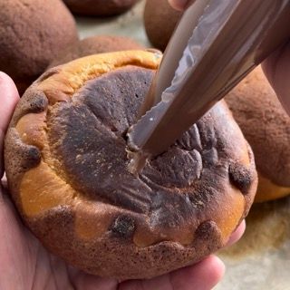 Un primo piano di una persona che tiene in mano un dolce con una sac à poche