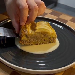 Crema inglese calda versata su una fetta di torta di mele.