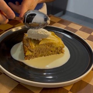 Piatto da dessert con fetta di torta di mele e una pallina di gelato alla vaniglia.