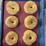 Sei ciambelle sono appoggiate su un vassoio blu su un tappetino rosso.