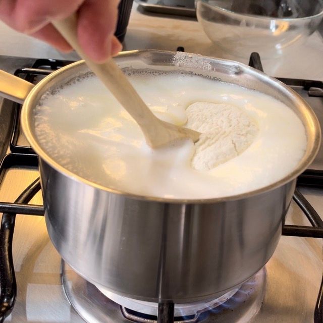 Una persona che mescola una pentola di latte con un cucchiaio di legno