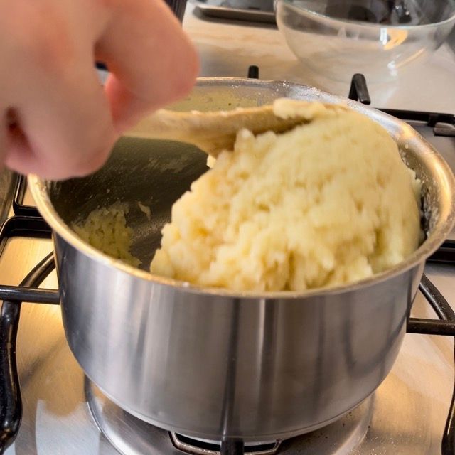 Una pentola di purè di patate viene mescolata con un cucchiaio di legno
