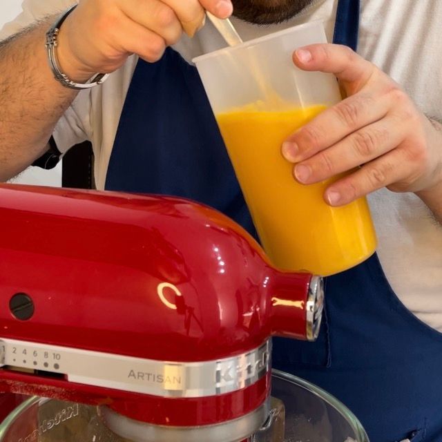 Un uomo sta versando del succo d'arancia in un frullatore KitchenAid