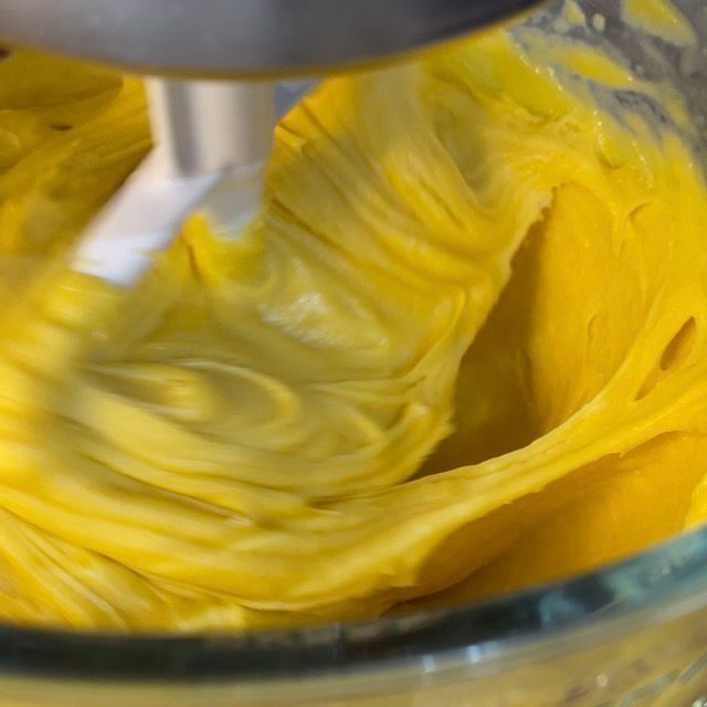 Un mixer sta mescolando un liquido giallo in una ciotola di vetro.