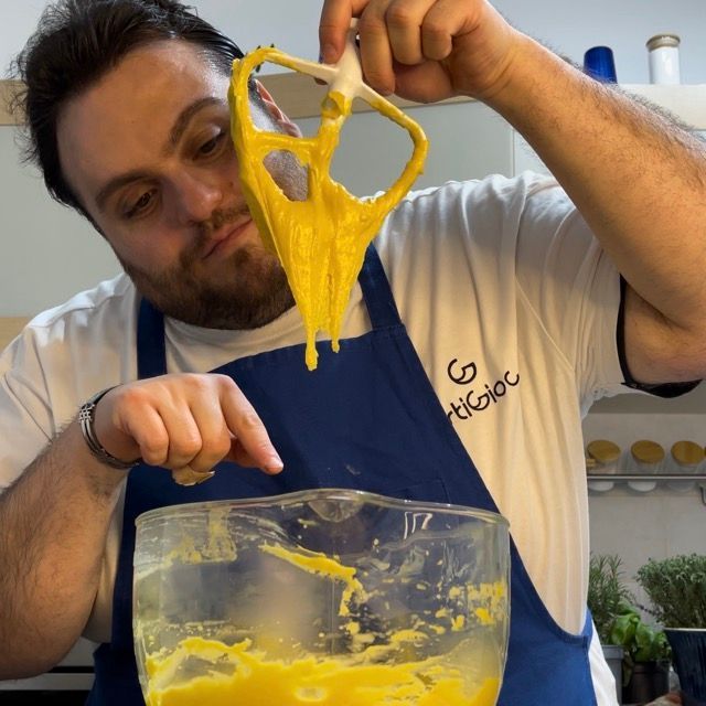 Un uomo che indossa un grembiule blu e una camicia bianca con la lettera g sopra