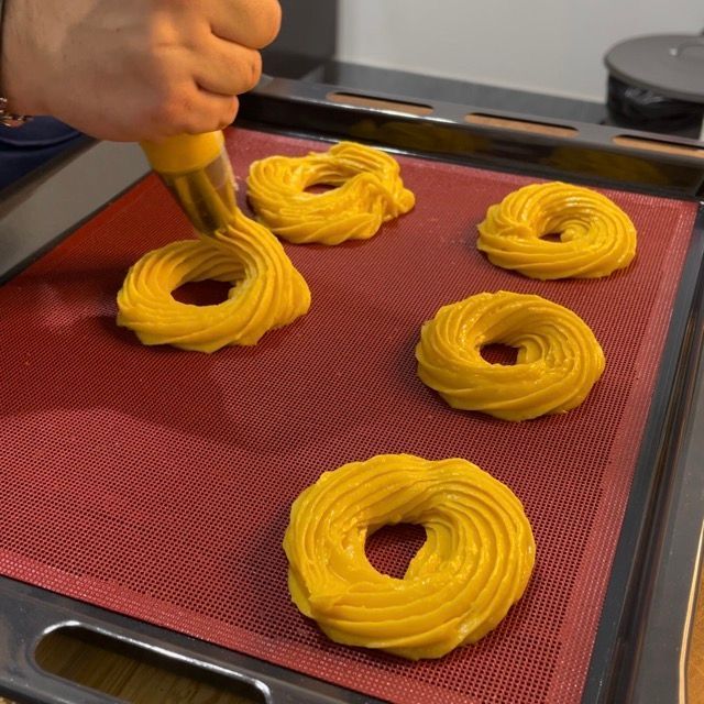 Una persona sta versando la glassa gialla su una teglia di biscotti