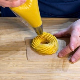 Una persona sta glassando una ciambella con glassa gialla