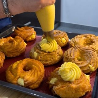 Una persona sta distribuendo la glassa gialla su un vassoio di pasticcini