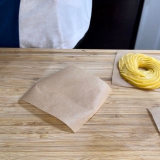 Una ciambella è avvolta in carta marrone su un tavolo di legno