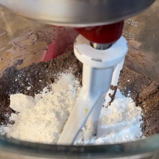Un mixer sta mescolando zucchero a velo e cioccolato in una ciotola di vetro