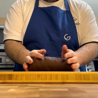 Un uomo che indossa un grembiule blu con la lettera g sopra