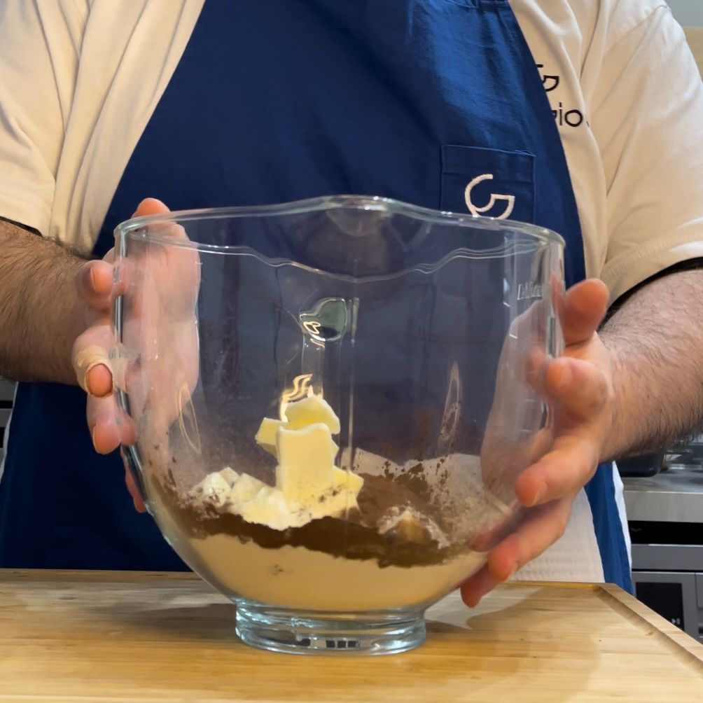 Un uomo tiene in mano una ciotola di vetro con del burro dentro