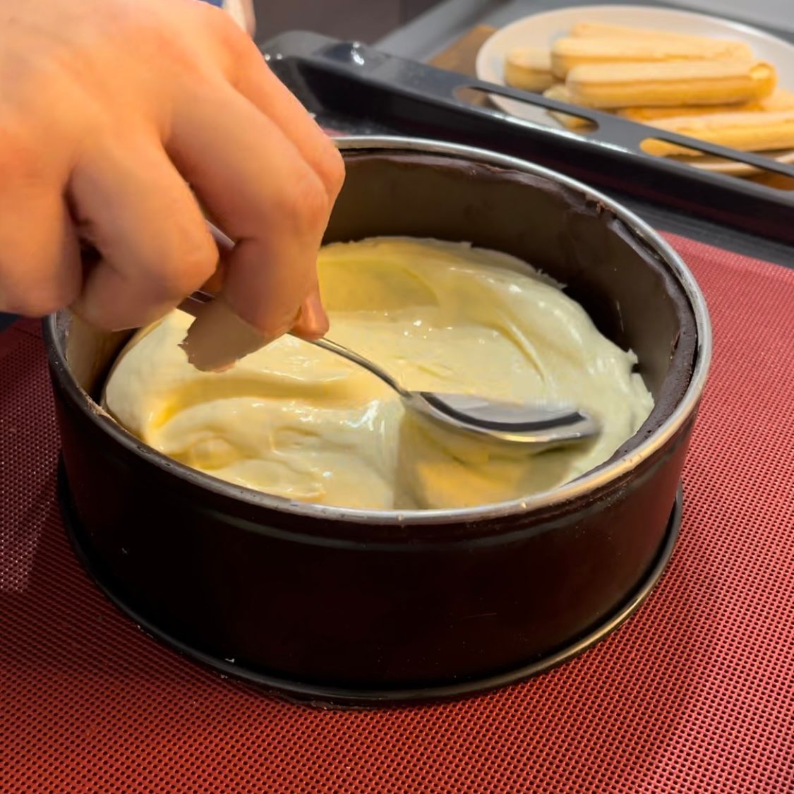 Una persona sta immergendo un cucchiaio nell'impasto di una torta