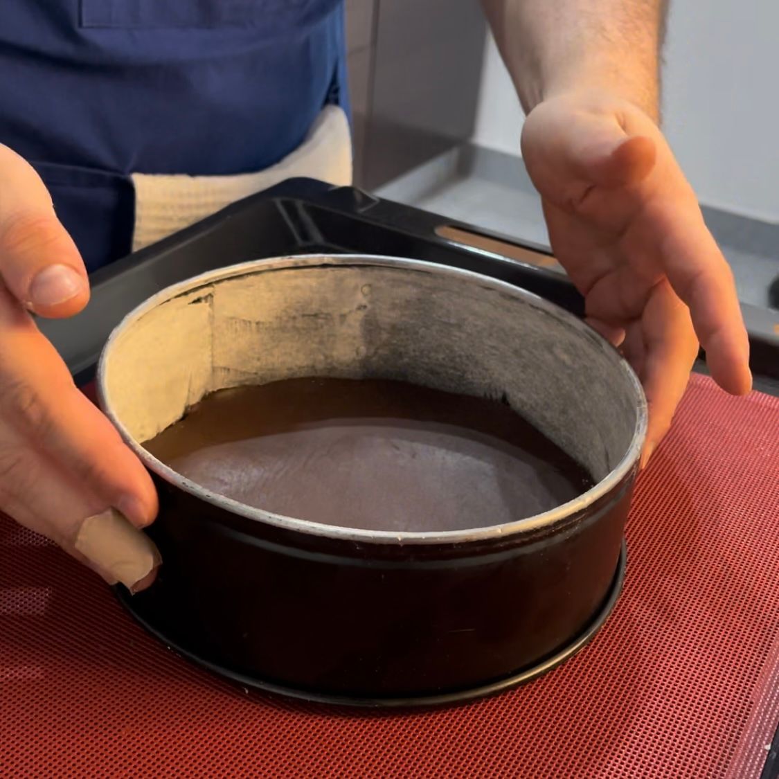 Una persona tiene in mano una padella con dentro un liquido marrone