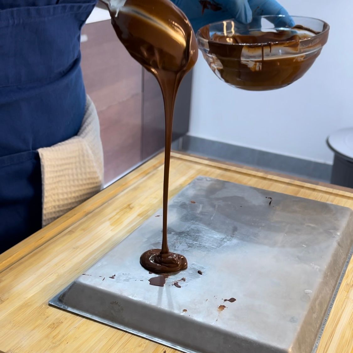 Una persona che versa del cioccolato in una ciotola con la lettera b sopra