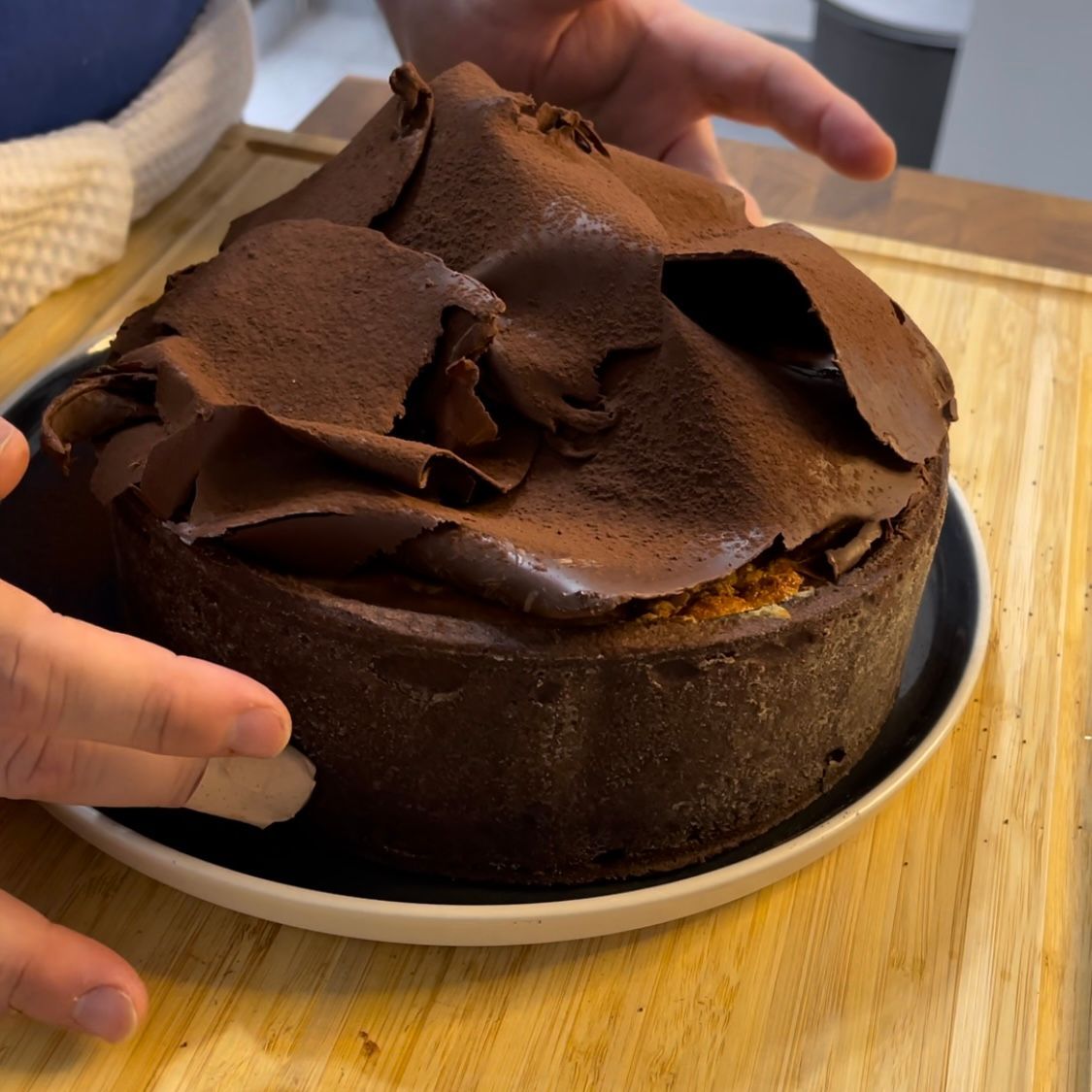 Una persona tiene in mano una torta al cioccolato su un piatto