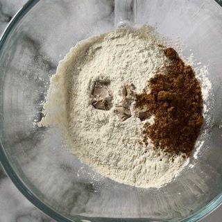 Una ciotola di vetro piena di farina e polvere marrone
