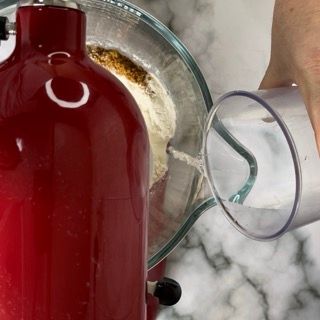 Una persona versa il latte in un bicchiere usando un frullatore.