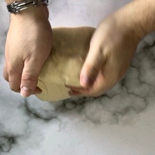 Una persona sta impastando una palla di pasta su un tavolo.