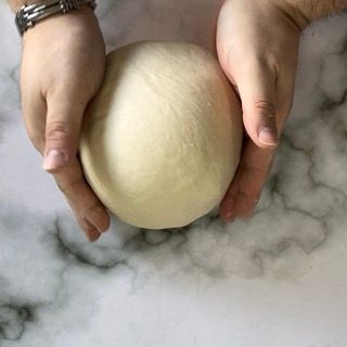 Una persona tiene in mano una palla di pasta.