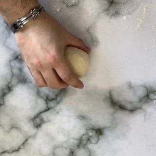 Una persona sta impastando l'impasto su un tavolo di marmo.