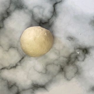 Una palla di pasta è appoggiata su una superficie di marmo.